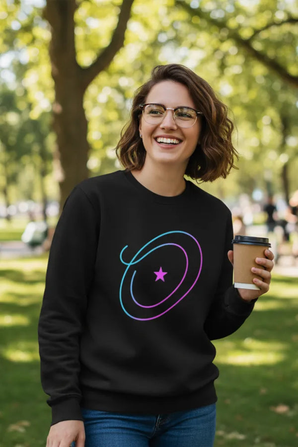 Person wearing a black sweatshirt with a colorful design, holding a coffee cup outdoors.