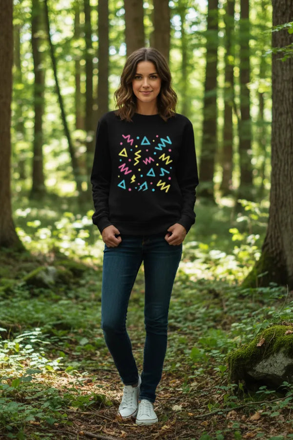 Woman wearing a black sweatshirt with colorful geometric patterns in a forest setting