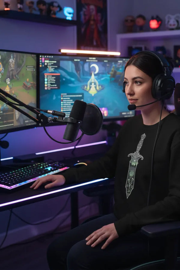 Person streaming or gaming with two monitors, a microphone, and a headset in a dark room.