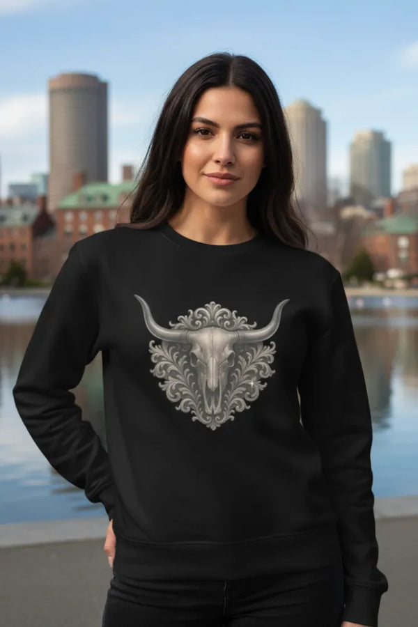 Woman wearing a black sweatshirt with a decorative bull skull design, standing in front of a city skyline.
