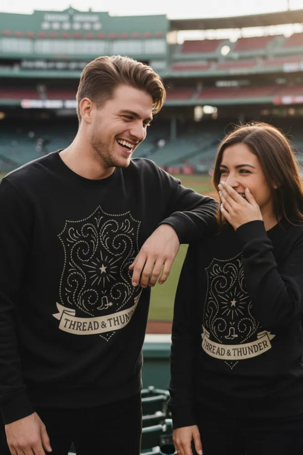 Two people wearing black sweatshirts with 'Thread & Thunder' design at a sports stadium.