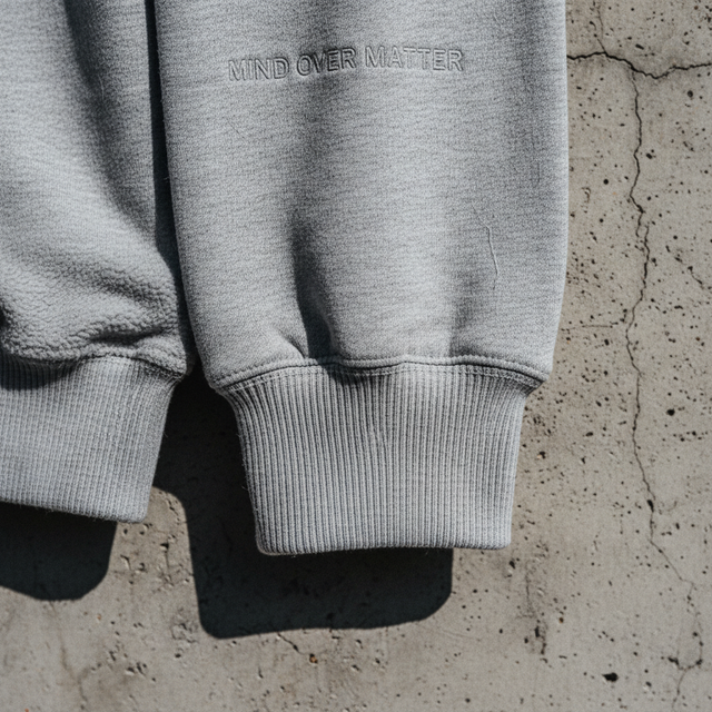 A high-fidelity shot of the Mind Over Matter sweatshirt draped over a concrete chair, highlighting the 280 gsm fabric weight and organic texture.