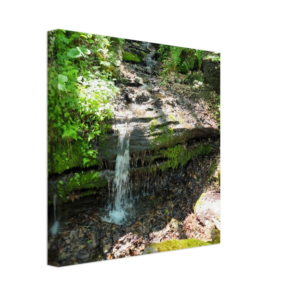 A tranquil waterfall cascading through a lush green forest, captured on a high-quality canvas print. Ideal for adding peaceful, nature-inspired elegance to any space.