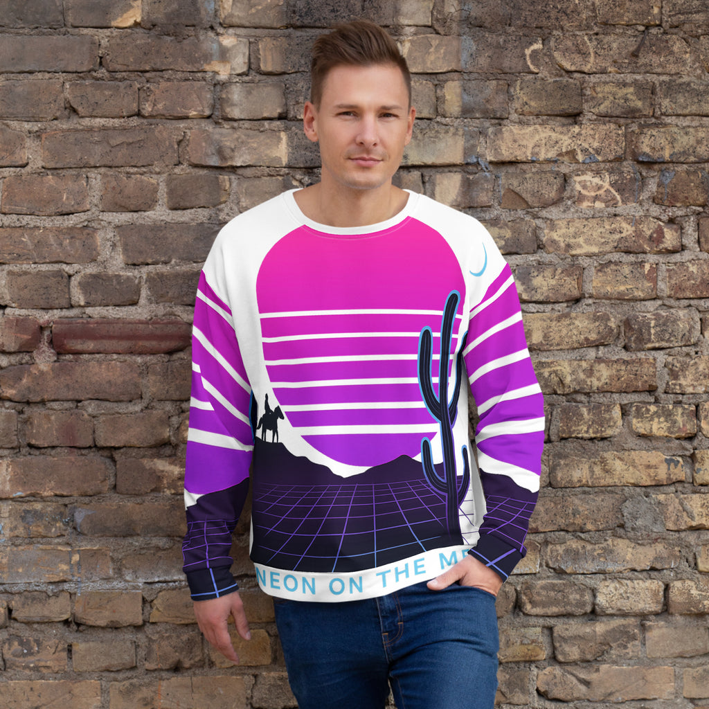 Man wearing a colorful sweater with a cactus design against a brick wall.