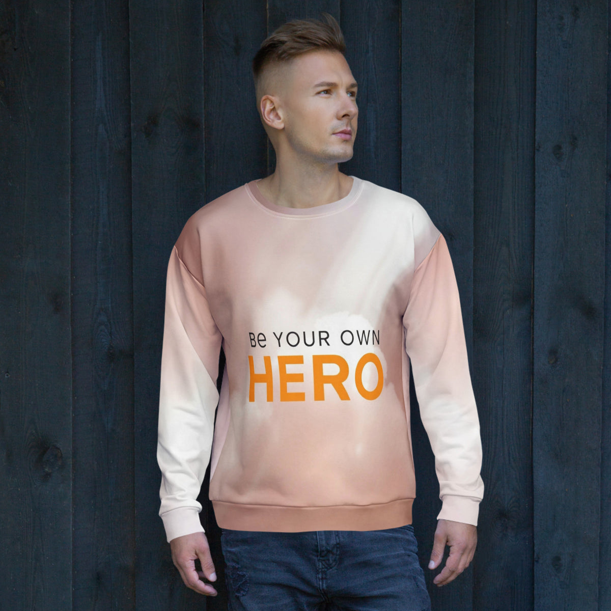 Man wearing a sweatshirt with 'Be Your Own Hero' text against a dark wooden background