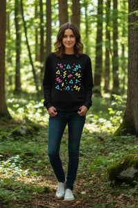 Woman wearing a black sweatshirt with colorful geometric patterns in a forest setting