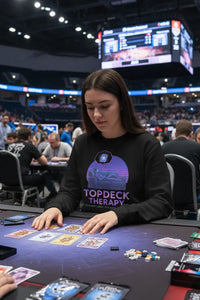 Person playing poker at a casino table with a large screen in the background
