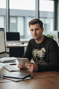 Man sitting at a desk in an office, holding a tablet.