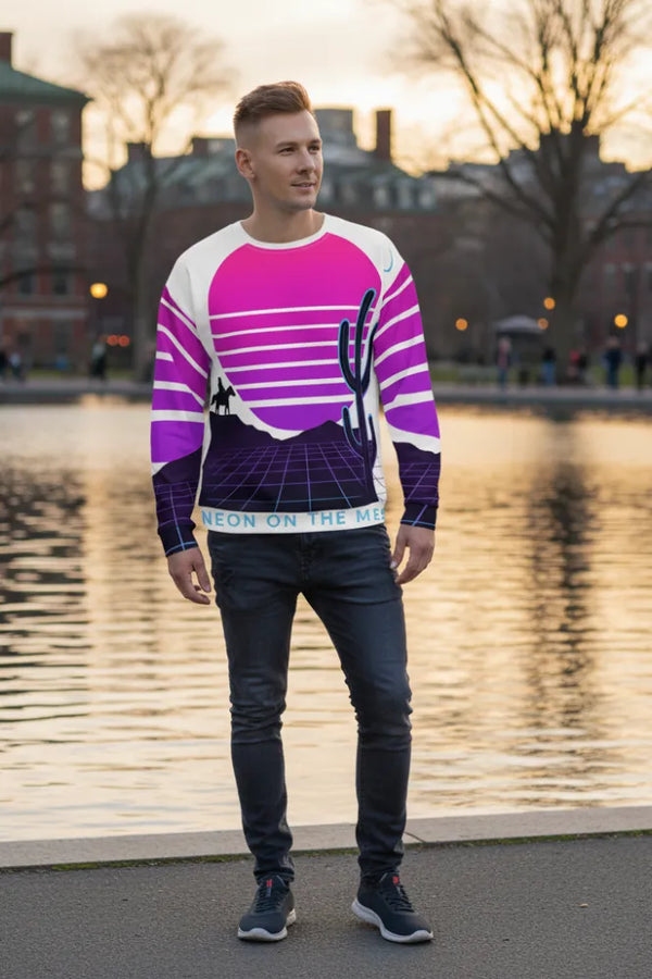 Man wearing a colorful sweater with a cactus design by a lake.