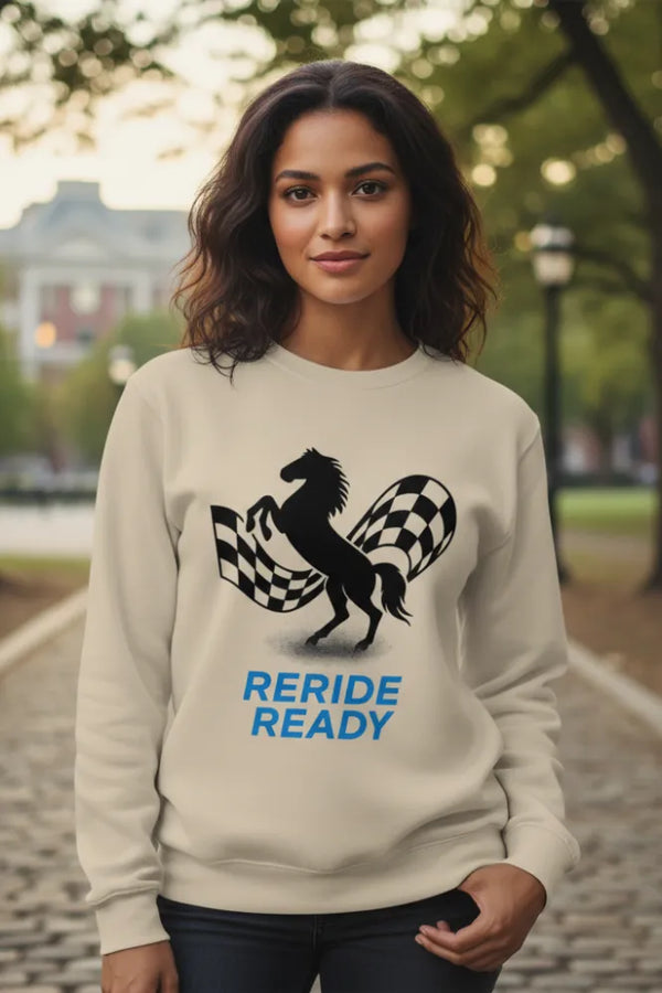 Woman wearing a beige sweatshirt with a horse and checkered flag design, text 'RERIDE READY', in an outdoor setting.