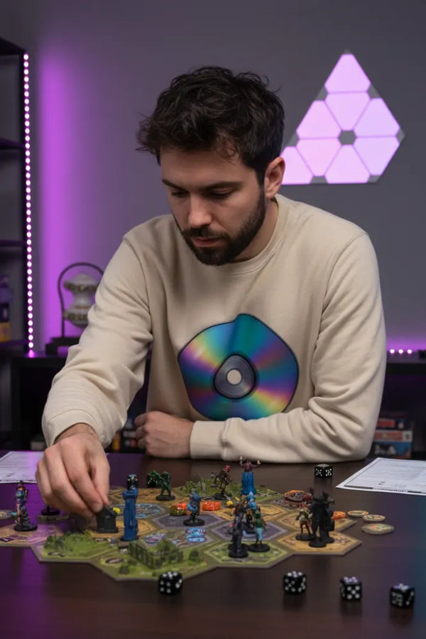 Man playing a board game with colorful dice and figures in a room with purple lighting and geometric light fixture.