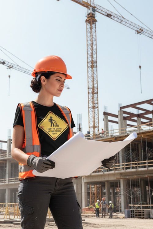 Person in construction attire holding blueprints with cranes and building structure in the background