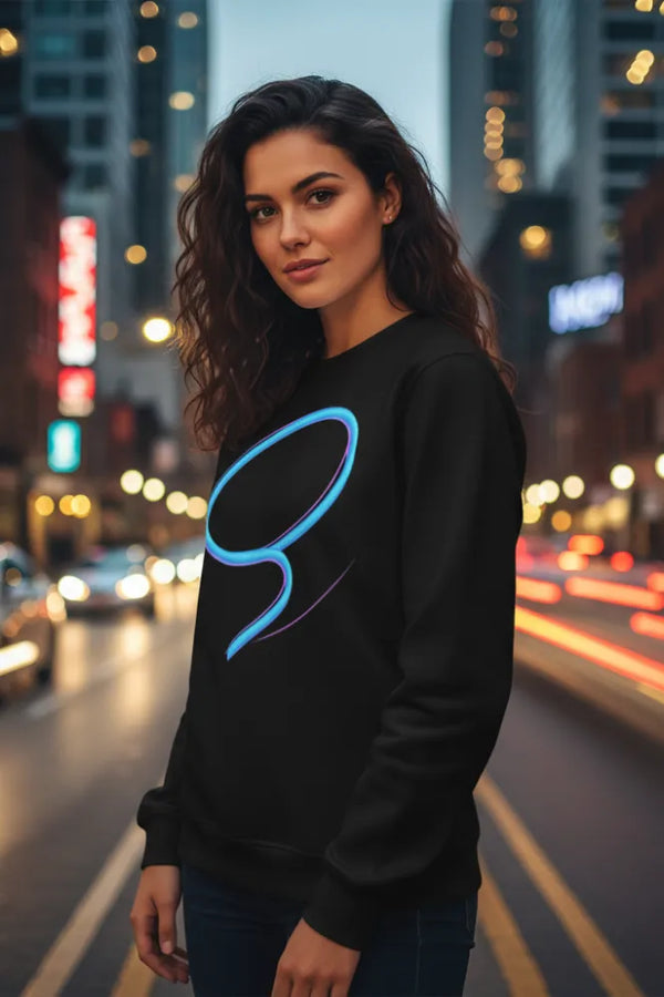Woman wearing a black sweatshirt with a blue logo on a city street at night.