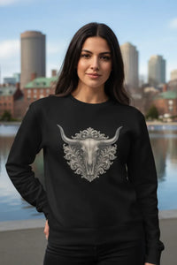 Woman wearing a black sweatshirt with a decorative bull skull design, standing in front of a city skyline.
