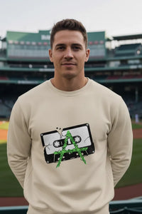 Man wearing a beige sweatshirt with a graphic design on a sports field background