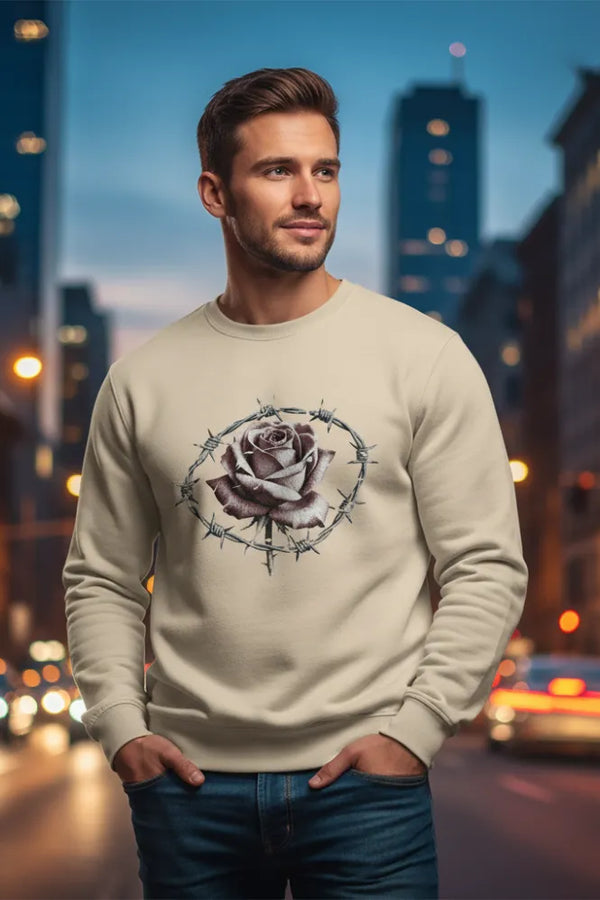 Man wearing a beige sweatshirt with a rose design in an urban setting at night.