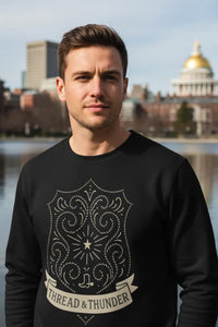 Man wearing a black sweatshirt with a design and text, standing in front of a cityscape with a prominent building.