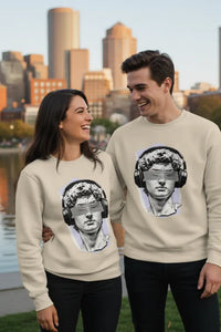 Two people wearing matching sweatshirts with a graphic design of a classical statue wearing headphones against a cityscape background.