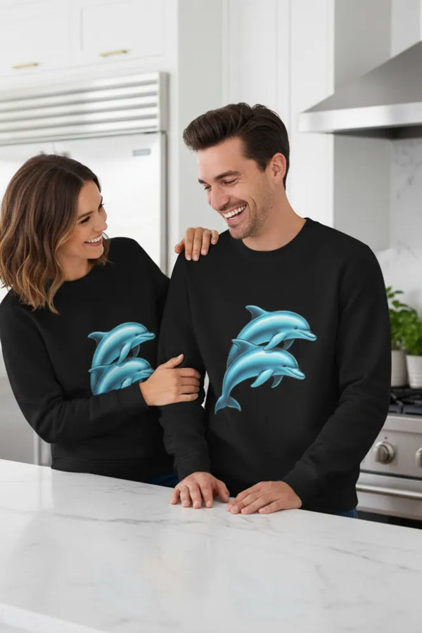 Two people wearing black sweatshirts with blue dolphin designs in a kitchen.