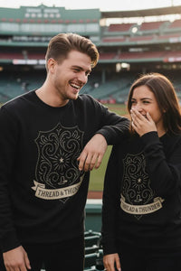 Two people wearing black sweatshirts with 'Thread & Thunder' design at a sports stadium.