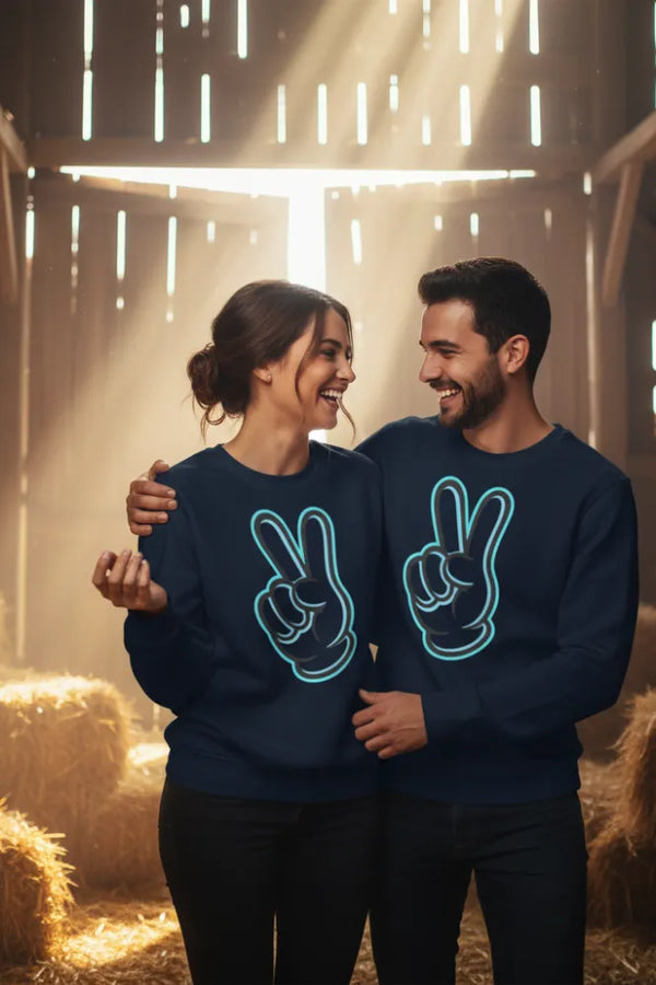 Two people wearing navy blue sweatshirts with peace sign designs in a barn setting.